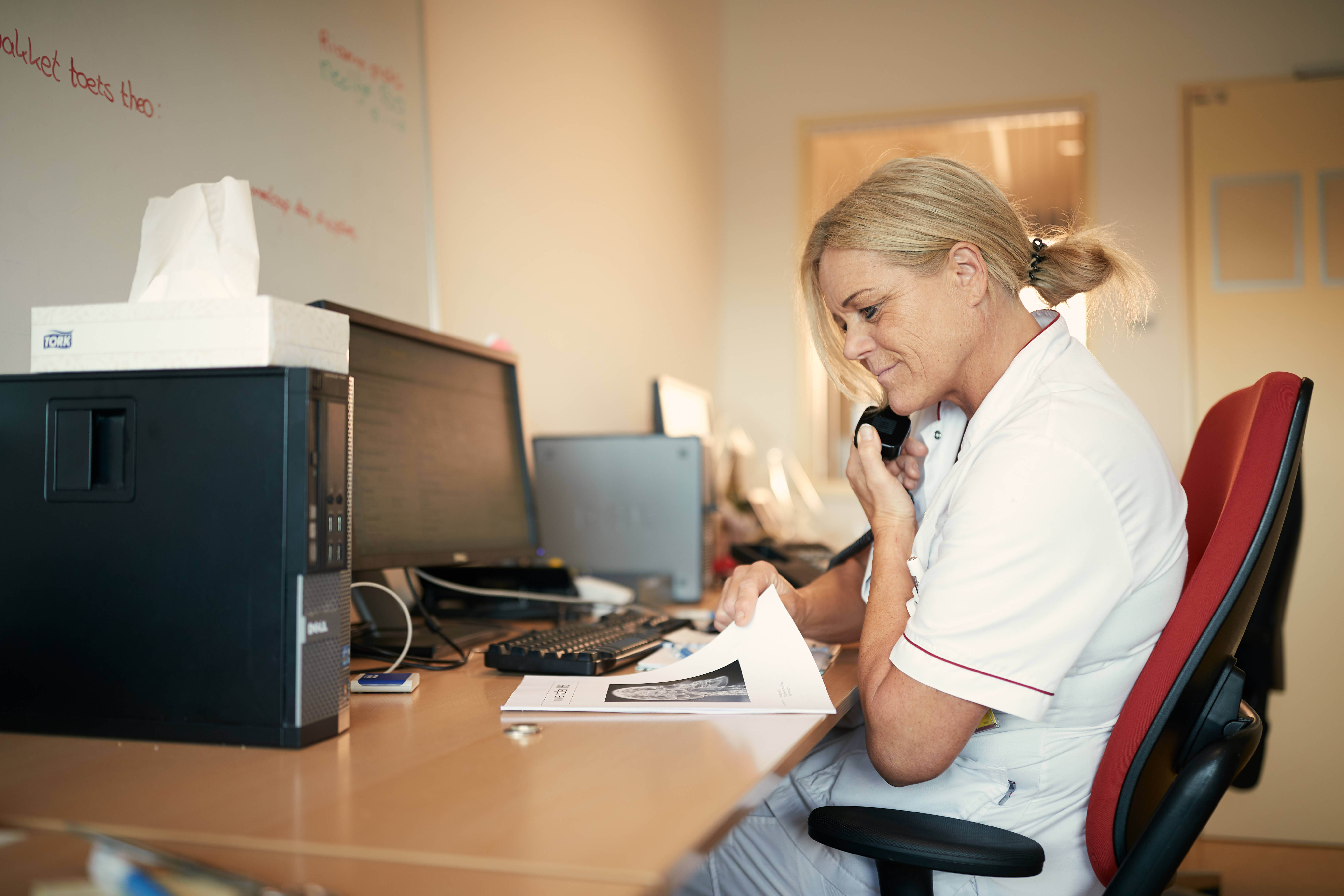 Verpleegkundige achter de computer en aan de telefoon